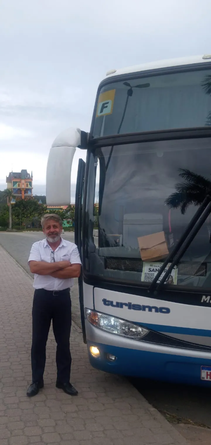 Sérgio, dono da i9+ Transportes, ao lado de um ônibus da empresa